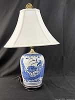 Front view of lamp with shade showing porcelain base, wood stand and finial