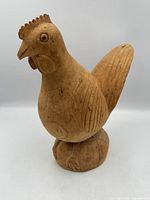 front view of carved wooden rooster on base