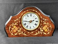 Front view of wood mantel clock showing dial, floral inlay and overall condition