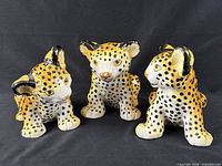 Front view of three ceramic baby leopard figurines