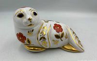 Front view of porcelain seal paperweight showing Imari floral decoration, blue eyes, gilded details