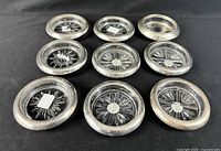 All nine coasters arranged face up showing starburst pattern and sterling rims