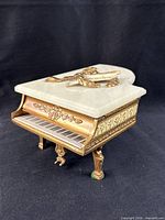 Three-quarter view showing lid closed, gilt body and keyboard