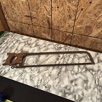 Full view of bow saw on table showing complete frame and handle