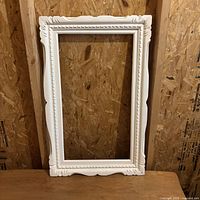 Full view of ornate white wooden frame leaning against wall