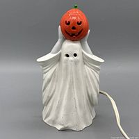 Front view of ceramic ghost lamp holding orange pumpkin