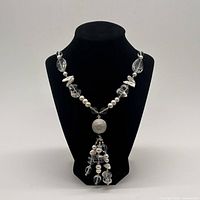 Full view of necklace on bust showing overall design and tassel pendant