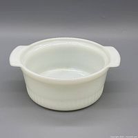 Front view of white milk glass casserole dish showing handles and ribbed base