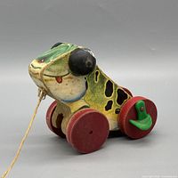 Left side view of toy showing frog graphics, wheels, cord