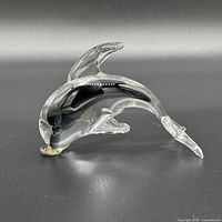 Side view of clear and smoky black glass dolphin with gold accent