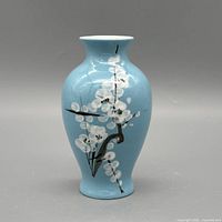 Front view of light blue ceramic vase with white blossom design