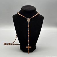 Full rosary on bust showing beads, medal, and crucifix