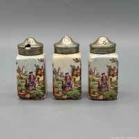 front view of three shakers showing pastoral design and lids