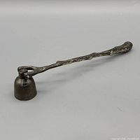 Full view of metal candle snuffer showing branch handle and bell head