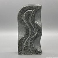Front view of entire soapstone sculpture showing wavy carved design and overall color
