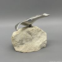 Profile view of metal seagull sculpture on stone base