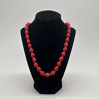 Front view of full red beaded necklace on display bust