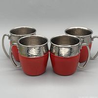 Front view of four red stainless steel mugs