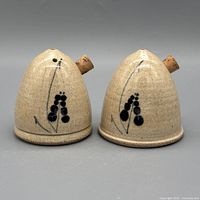 Front view of both stoneware shakers showing floral motif and pour holes