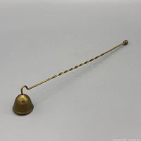 Full view of brass candle snuffer showing length and form