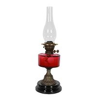 Full view showing lamp with red reservoir, brass fittings, clear chimney, black base