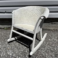 Three-quarter front view of white wicker child rocking chair showing overall design and finish