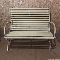 Full view of cream metal slat bench