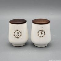 front view of both shakers showing gold monograms and wood lids