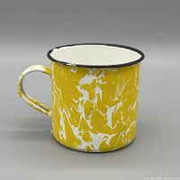 Front angled view showing yellow and white marbled enamel mug with black rim
