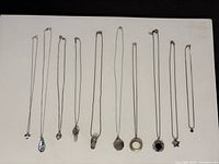 Ten silver necklaces laid out side by side