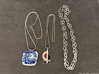 Three sterling silver necklaces with two pendants displayed on dark background