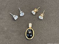 Pendant and two pairs of stud earrings on display