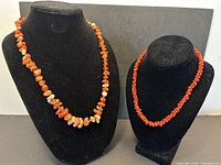 Both coral necklaces on display busts showing size difference