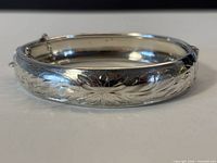 Side view of sterling bangle showing engraved floral design