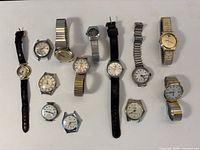 All thirteen watches laid out showing variety of styles, straps and cases