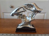 Front view of silver-tone statue on wood base with ruler for scale