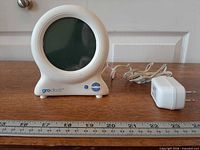 Front view of Groclock and power adapter with ruler for scale