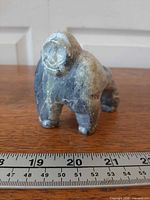 Front view of stone bear carving against ruler for scale