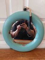 Front view of round turquoise mirror showing frame and mirror surface