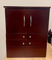 Front view closed showing mahogany finish, dual doors, four drawers, chrome pulls