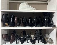 Shelf view showing 10 pairs black, brown and silver heels plus white sneakers on upper shelf