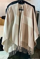 Front view of beige and cream shawl wrap with fringed hem