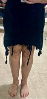 Full front view of black skirt worn, showing length and tassel trim