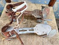 Top view of both adjustable clamp-on skates showing metal frames, leather and plastic straps
