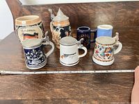Group of seven miniature steins with tape for scale