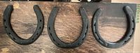 Three black steel horseshoes laid flat on wood surface