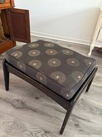 Full view of ottoman showing wood frame and cushion