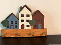 Front view of painted wooden wall hook rack with house motif