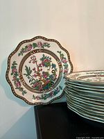 Stack of scalloped dinner plates and one displayed plate showing Indian Tree pattern