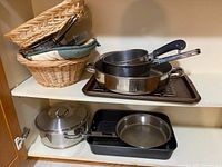 Cookware and baskets on cupboard shelf